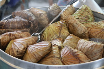 The rice wrapped in Lotus leaf are steaming in metal round shape steamer in Thailand. Close up view.