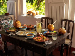 Breakfast on a vintage table overlooking the garden. Eggs, toasts, lemonade, coconuts.