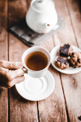 The woman's hand grabs the teacup and raises it.