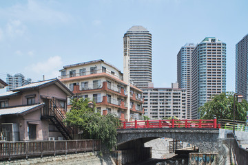 Red bridge over urban canal with mix of old and new buildings