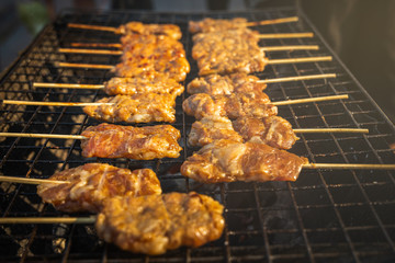 Hot and fresh Thai grilled pork skewers , popular street food breakfast in Thailand, on charcoal stove.