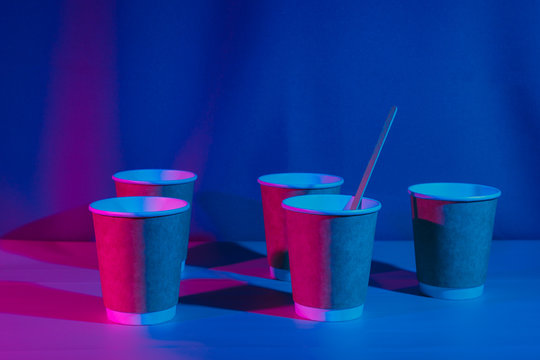 Paper cups for coffee on the table in neon lighting.