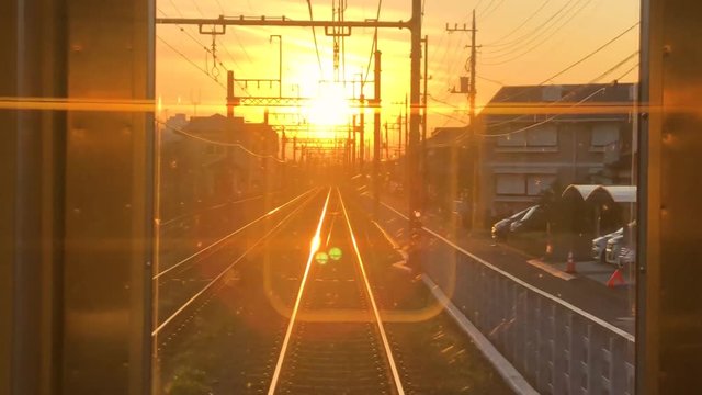View from back of train through a window of a sunset hitting the tracks in Tokyo, Japan.