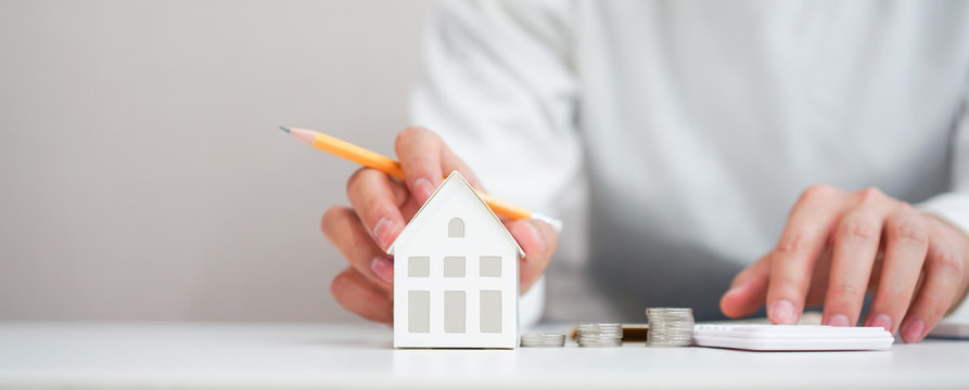 Close Up Young Man Hand Touching House's Model For Check And Summary Expense Of Home Loan Mortgage For Refinance Plan , People Lifestyle Concept	