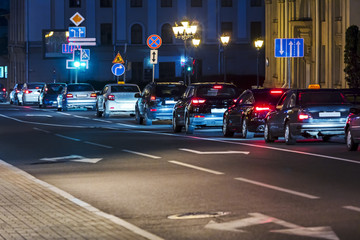 cars standing in jam on city night street. buildings and city illuminated with colorful lights