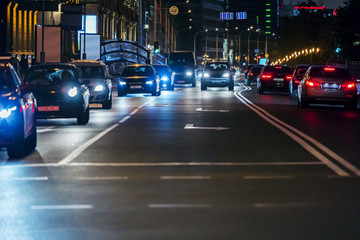 Fototapeta na wymiar cars driving in the street during evening rush hour. headlights illuminating dark road