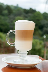 Glass cup served with Capuccino coffee, aromatic coffee from Guatemala served outdoors, relaxing and natural space.