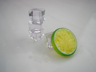 Four piece of ice.White background in front of a pile of ice and yellow green lemon slices
