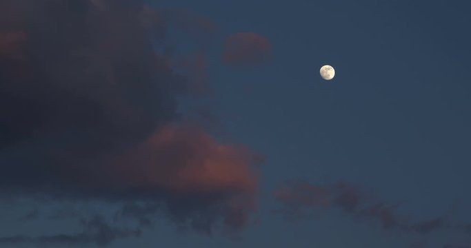 view of the moon in the pre-twilight sky in a winter time-lapse