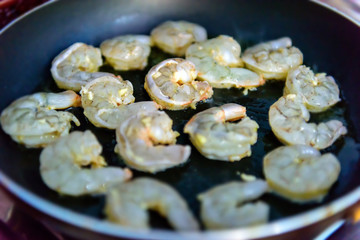 Process of roasting fresh shrimp without shell, selective focus. Peeled king prawns in a pan, close-up. Seafood, a source of protein.