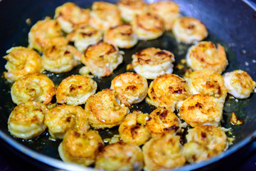 Process of roasting peeled shrimp with garlic in a frying pan, close-up. Prawns golden fried. Seafood delicious.