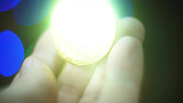 Golden sparkling bitcoin rotates on a palm background. The desire to get rich. A trembling hand wants to take a gold coin. Selective focus