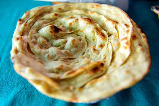 Paratha, round flaky Indian bread from whole wheat, selective focus, close-up. Laacha paratha in restaurant traditional indian kitchen.