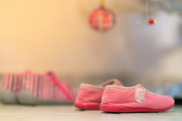 Fototapeta na wymiar Little girl shoes under Christmas tree to receive presents