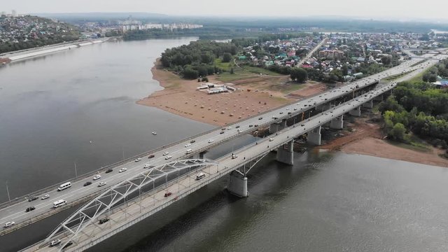 White River in the city center on the background of private houses with colorful roofs on a slope with green trees and modern high-rise buildings. Belsky Bridge, Ufa, Bashkortostan, Russia.