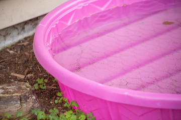 A view of calm water inside a children's small pink swimming pool.