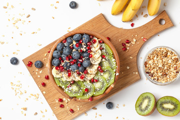 Healthy summer breakfast with granola, blueberries, bananas, kiwi and pomegranate. Healthy food nutrition, snack or breakfast. Top view. 