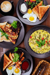 Breakfast foods includes pancakes, eggs and bacon, biscuits, scrambled eggs, cinnamon muffins, fresh blueberries, pancake balls, and cinnamon rolls with icing.