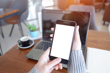 Mockup picture of business woman’s hands or man's hands holding smart phone with white blank screen in modern place.