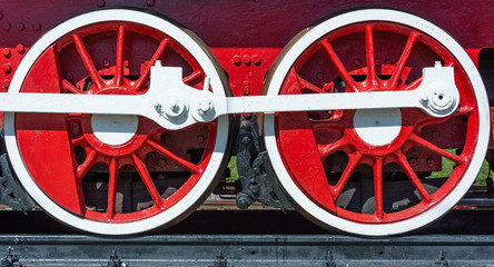 Train wheels painted vivid red and white, bright sunny day.