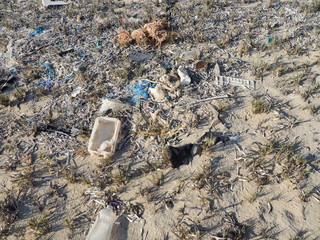 Environmental pollution. Sand beaches polluted with pieces of plastic waste. Micro plastics debris on the beach. Pieces of plastic residues