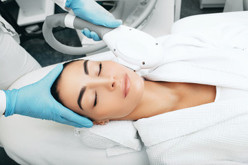 Obraz na płótnie Canvas Brunette woman during removes brown spots on face, Beautician using ELOS rejuvenation technology