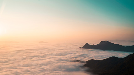 The sunrise above the clouds surrounding by the mountains, Top view.