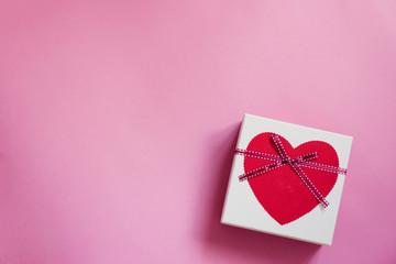 Gift box with a heart and a bow on a pink background