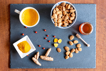 Golden milk, a traditional Indian drink that has its roots in Ayurveda. The ingrediends are turmeric powder, almond milk and honey. Composition flat lay.