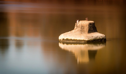 Una sola roca reflejada en el río con tonos dorados y efecto seda