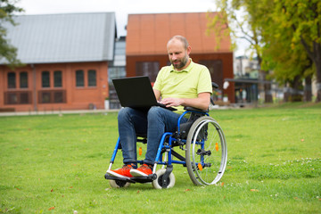 man on wheelchair working on laptop