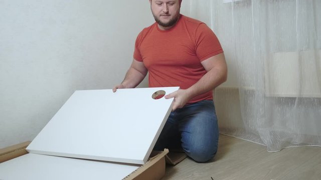 Man collects boxes from chipboard with a screwdriver