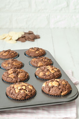 Tray of chocolate muffins with pieces of white chocolate.