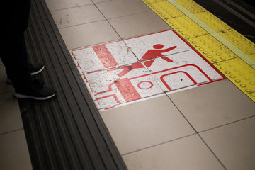 Red spain tripping hazard symbol on the underground subway/metro platform warning passengers to be aware of the gap between the train and the platform. Mind the gap and be careful of tripping.