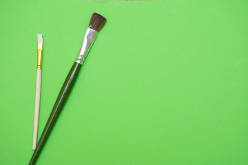 Green art flatlay concept with green and white paintbrushes illustrating creativity, inspiration, and artistic expression.