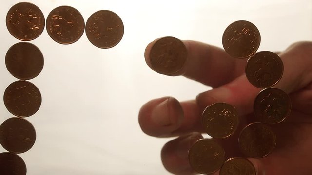 View from below as the hand throws gold coins. Moves them, collects them in the shape of a heart or columns.White background. Indoors.