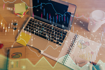 Double exposure of man's hands writing notes of stock market with forex chart.