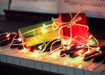 gift boxes on piano key board with glowing and colorful string lights. Christmas , New year , Valentine's day concept.