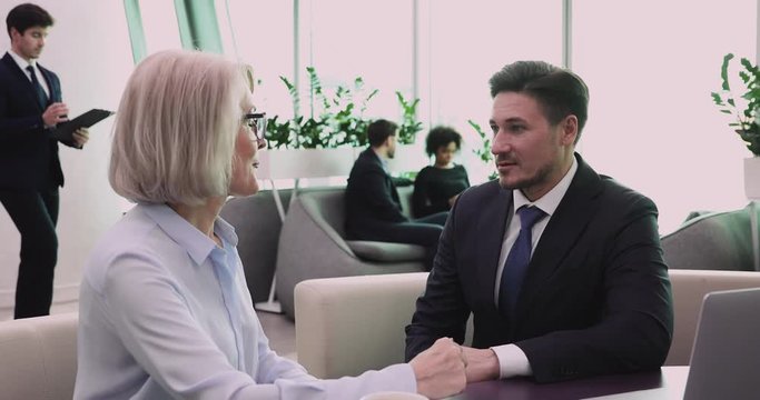 Businessman employer listen old businesswoman job candidate during job interview