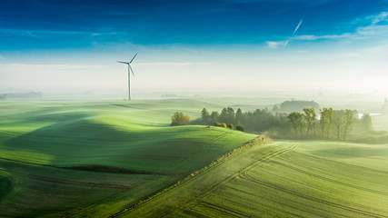 Foggy wind turbine at sunrise, view from above