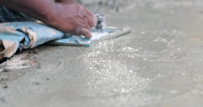 Builder worker smoothing cement at industrial construction work