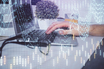 Multi exposure of graph with man typing on computer in office on background. Concept of hard work....
