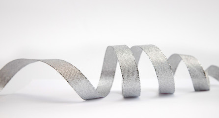 Silver gift ribbon twisted in rings lies on a white background. Design element