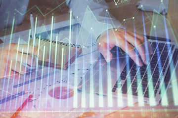 Forex graph with businessman working on computer in office on background. Concept of hardworking. Double exposure.