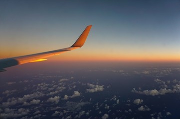 Fototapeta premium Blick aus dem Flugzeug bei Sonnenaufgang über den Wolken mit Tragfläche im Bild über Costa Rica