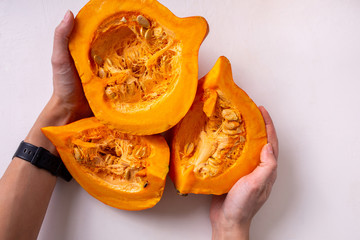 Pumpkin cut into pieces on a light background. Autumn food concept. Harvest in the hands.