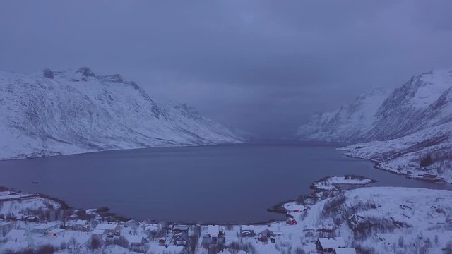 Flying high over small town in northern Norway, mountains and fjord in background.