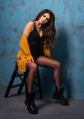 Beautiful sensual woman in black body suit posing in the studio over grey concrete walls background