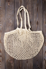 Fototapeta premium Reusable mesh product bag on a wooden table, top view. Zero waste concept.