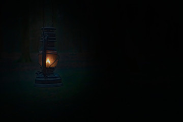 Fototapeta na wymiar Light in the darkness. Blurred background image of a glowing lantern against dark night time. Light in dark forest / wood. 